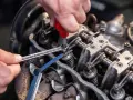 Mechanik reguluje luzy zaworowe silnika, używając klucza i szczelinomierza.