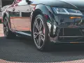 Błyszczące, czarne auto sportowe z felgami i widocznym rantem ochronnym opony.