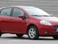 Czerwony Fiat Grande Punto, często chwalony w fiat grande punto opinie, stoi na szarym tle.