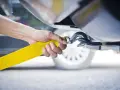 Dłoń mocuje żółtą linę holowniczą do haka. To kluczowy moment, jak holować auto, by bezpiecznie przetransportować pojazd.