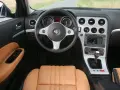 Wnętrze Alfa Romeo 159 1.9 JTD z beżową skórzaną tapicerką, kierownicą i konsolą środkową.