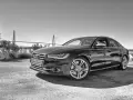 Elegancki czarny Audi S6 C7 z charakterystycznym grillem i felgami, zaparkowany na tle mostu wiszącego.