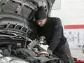 Mechanik z latarką bada silnik Renault, szukając przyczyny błędu DTC P0380.