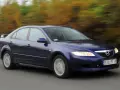 Granatowa Mazda 6 GG jedzie po drodze, za nią rozmyte drzewa w jesiennych barwach.