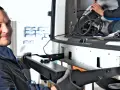 Mechanik z uśmiechem montuje hak w aucie. W tle widać drugą osobę pracującą przy instalacji.