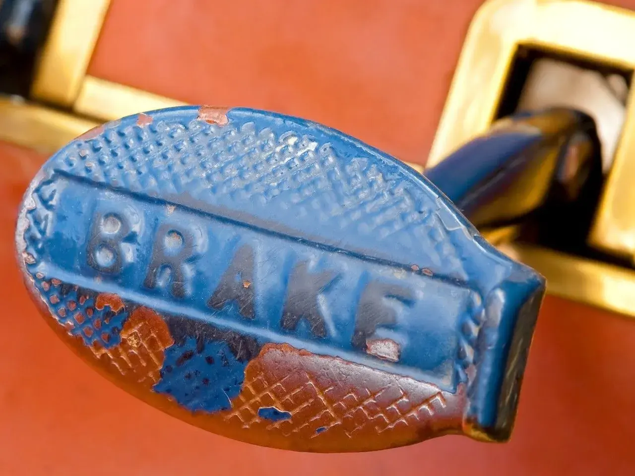 Stary, niebieski uchwyt hamulca z napisem "BRAKE". Zastanawiasz się, jaki smar do prowadnic hamulcowych?