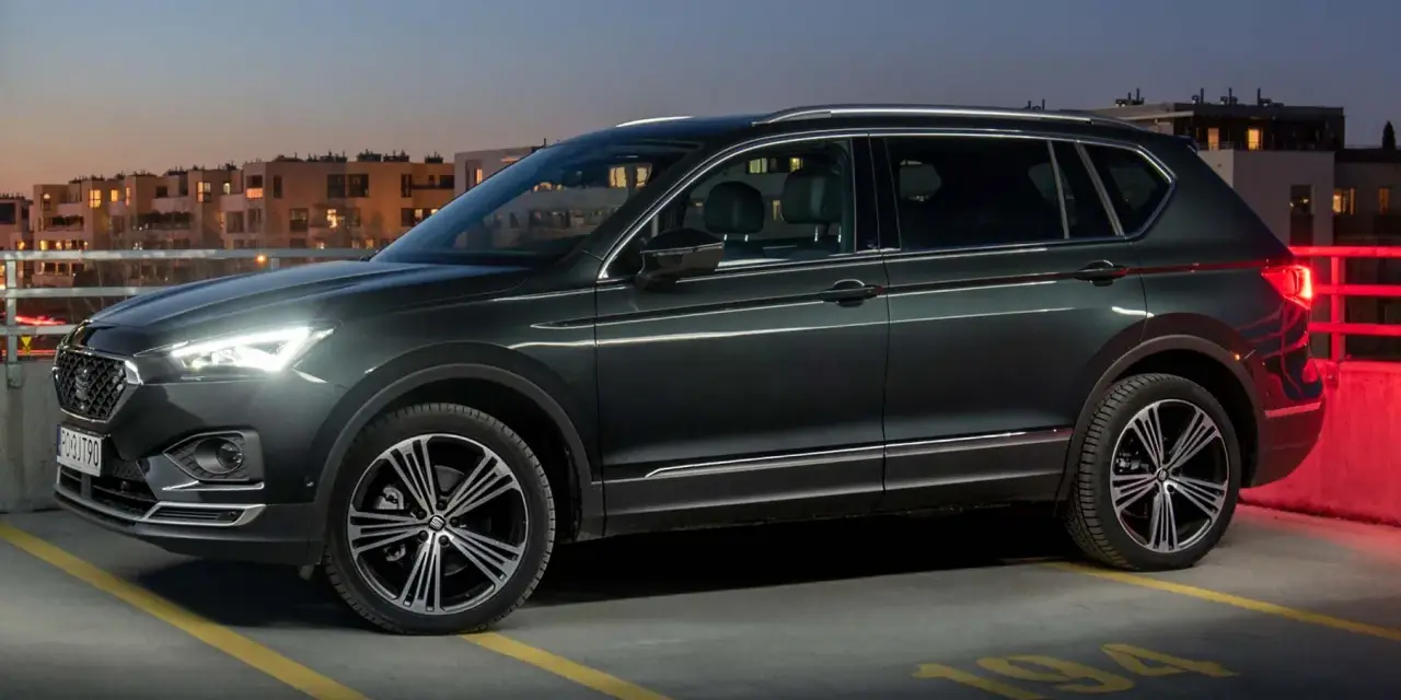 Ciemnozielony SUV, jeden z najbardziej polecanych samochodów 7-osobowych, zaparkowany na dachu parkingu nocą.