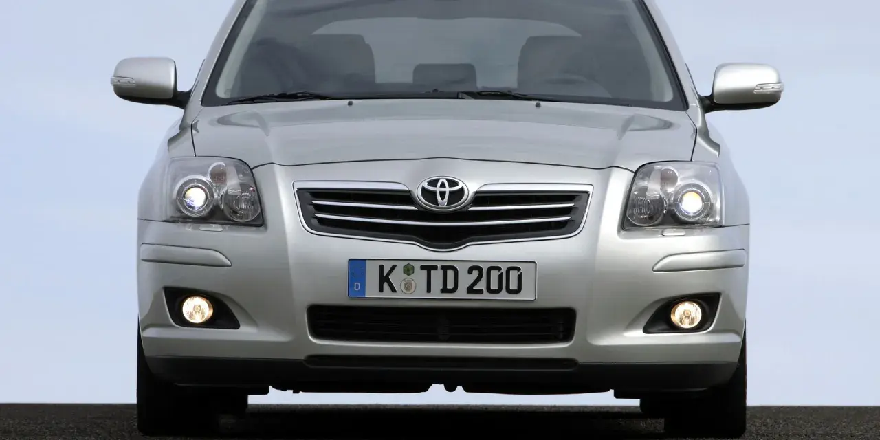 Srebrny Toyota Avensis T25 z włączonymi światłami mijania i przeciwmgielnymi, gotowy do podróży.