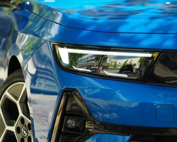 Nowoczesne, jasne światła do jazdy dziennej w niebieskim samochodzie, odbijające otoczenie.