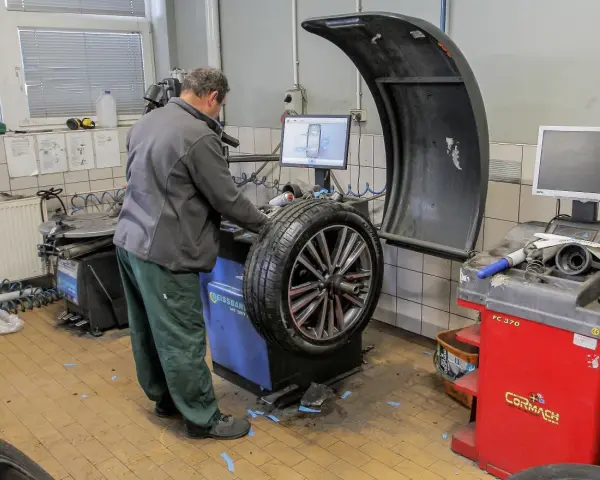 Mechanik sprawdza na maszynie, ile kosztuje wyważenie kół. Na ekranie widoczny jest schemat felgi.