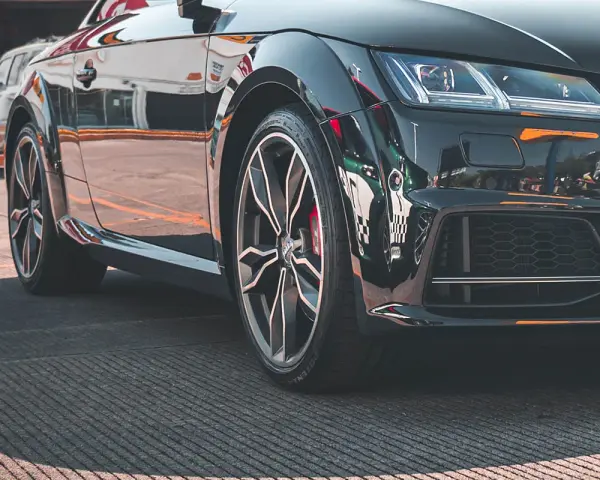 Błyszczące, czarne auto sportowe z felgami i widocznym rantem ochronnym opony.