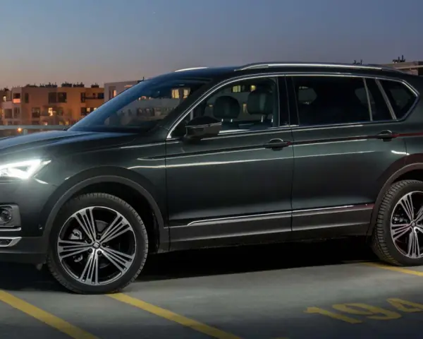 Ciemnozielony SUV, jeden z najbardziej polecanych samochodów 7-osobowych, zaparkowany na dachu parkingu nocą.