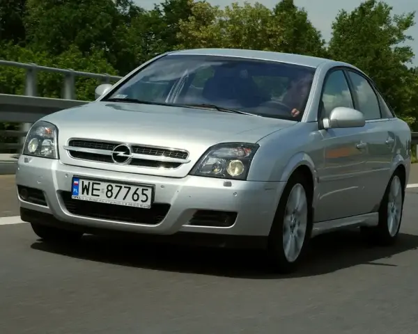 Srebrny Opel Vectra C GTS z polskimi tablicami WE 87765 jedzie po drodze, otoczony zielenią.