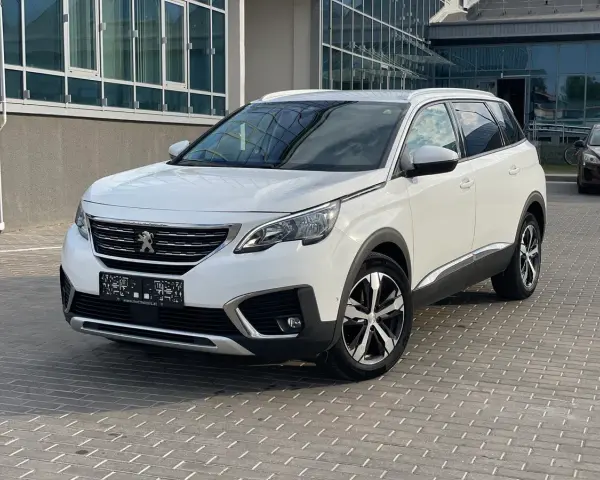 Biały Peugeot 5008 na parkingu. Wiele osób szuka peugeot 5008 opinie, ten SUV to świetny wybór.