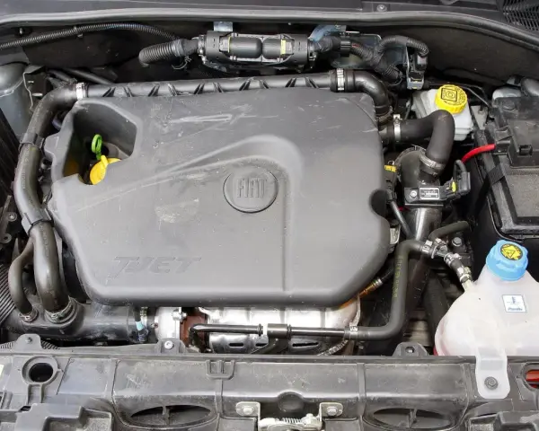 Silnik 1.4 z Fiata Grande Punto. Widoczny plastikowy kolektor, akumulator i zbiornik płynu chłodniczego.