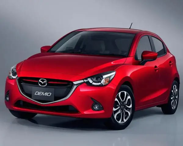 Czerwona Mazda Demio z błyszczącym grillem i reflektorami.