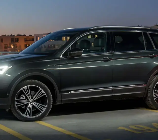 Ciemnozielony SUV, jeden z najbardziej polecanych samochodów 7-osobowych, zaparkowany na dachu parkingu nocą.