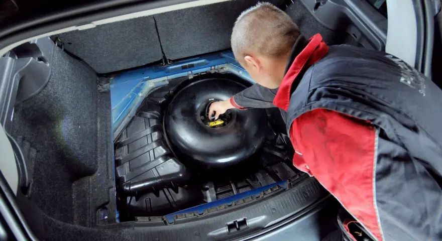 Mechanik sprawdza butlę LPG w bagażniku. Dowiedz się, ile kosztuje legalizacja butli LPG i jakie są formalności.