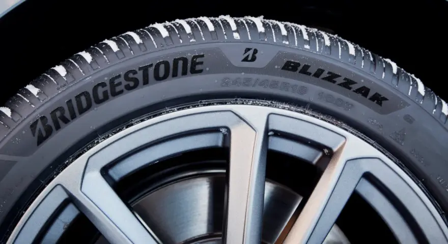 Opony zimowe Bridgestone Blizzak na feldze, pokryte śniegiem. Wiele pozytywnych opony Bridgestone opinie potwierdza ich jakość.