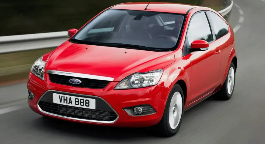 Czerwony Ford Focus MK2 1.6 benzyna w ruchu na krętej drodze.