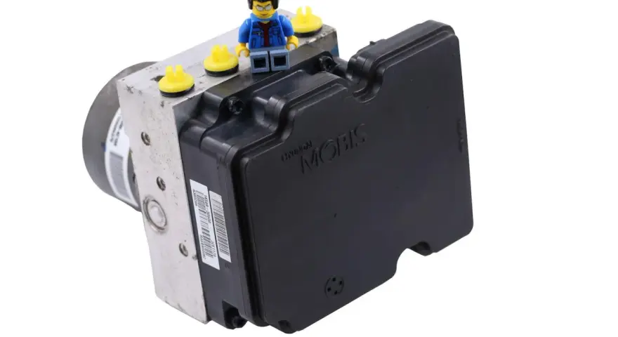 Moduł ABS Hyundai Mobis. Może być powiązany z błędem DTC C1201 Toyota. Figurka Lego na górze.