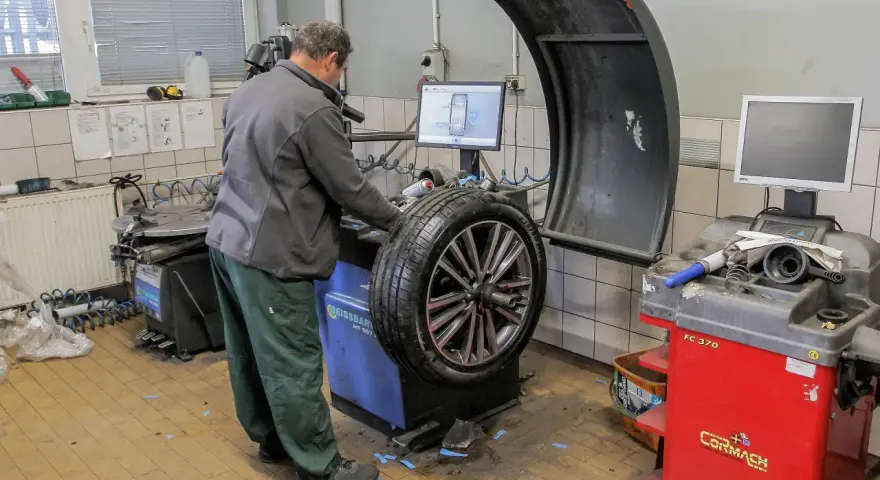 Mechanik sprawdza na maszynie, ile kosztuje wyważenie kół. Na ekranie widoczny jest schemat felgi.