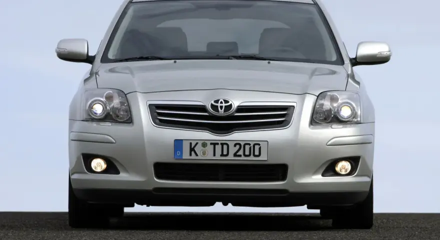 Srebrny Toyota Avensis T25 z włączonymi światłami mijania i przeciwmgielnymi, gotowy do podróży.