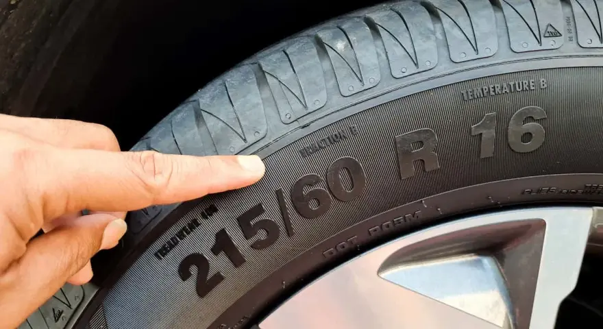 Palec wskazuje na oznaczenie opon zimowych 215/60 R16.
