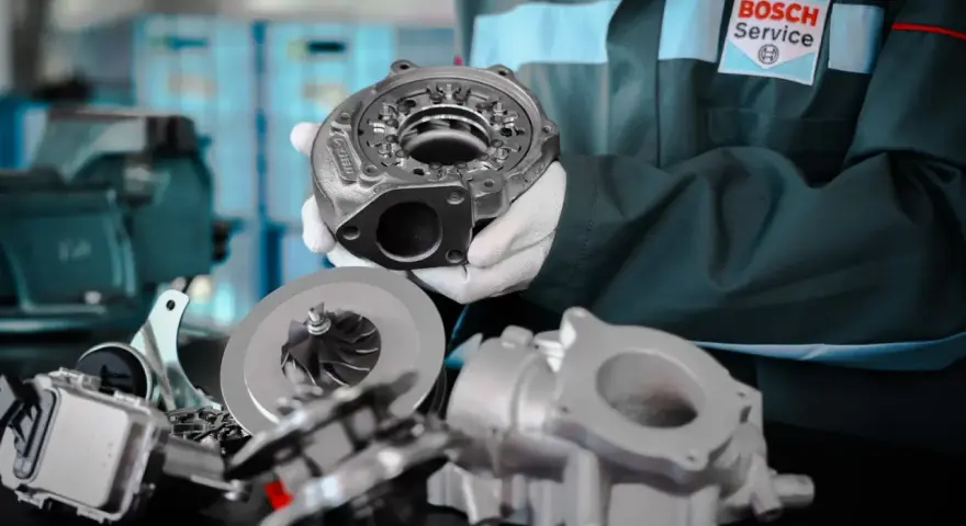 Mechanik w rękawiczkach prezentuje turbosprężarkę, element p0299, obok wirnika i obudowy.