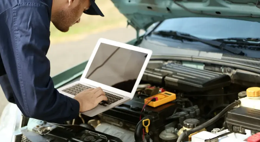 Mechanik diagnozuje usterkę w Oplu p2279, używając laptopa i multimetru.