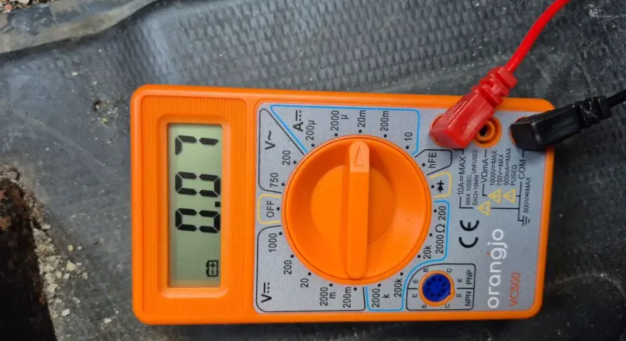 Pomarańczowy multimetr pokazuje 0.07A, co jest pomocne, gdy chcesz sprawdzić pobór prądu w samochodzie.
