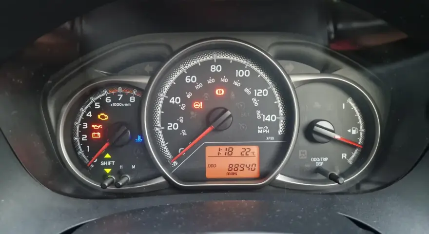 Kontrolka silnika świeci się na desce rozdzielczej Toyoty, wskazując błąd DTC P1604. Odometer pokazuje 88940 mil.