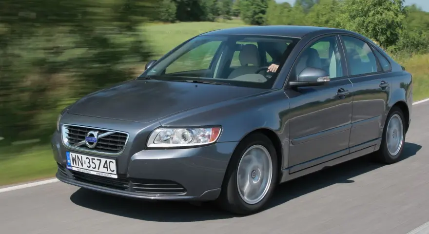 Szary Volvo S40 2.0 diesel w ruchu, z rozmazanym tłem zieleni i drogi.