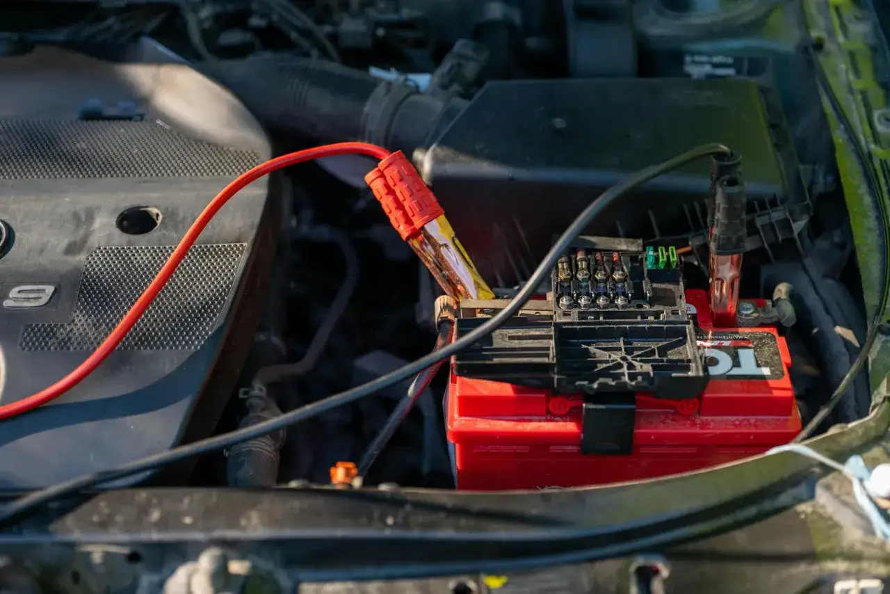 Podłączanie kabli rozruchowych do akumulatora. Czasem to pomaga, jak skasować błąd check engine bez komputera.