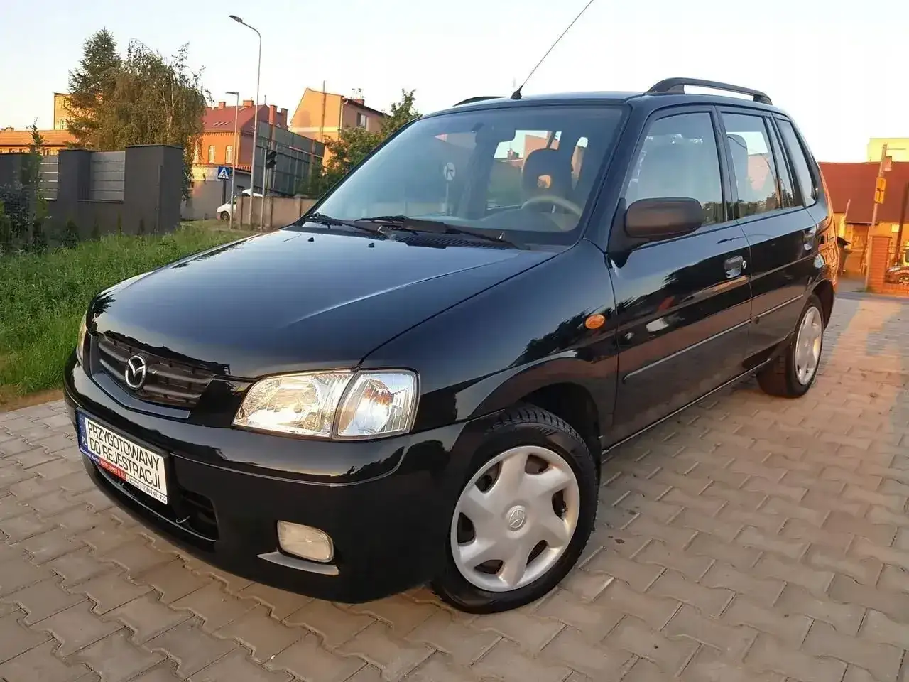 Czarna Mazda Demio gotowa do rejestracji, zaparkowana na kostce brukowej.