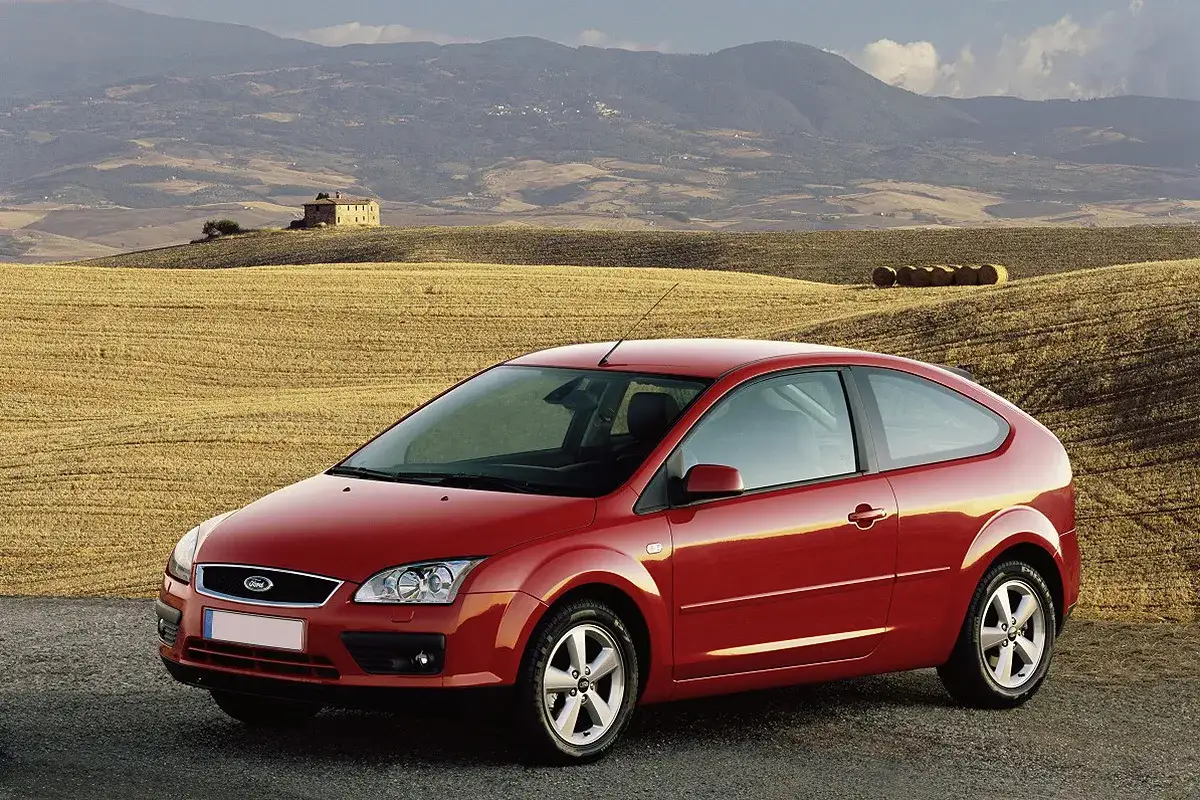 Czerwony Ford Focus MK2 1.6 benzyna na tle toskańskiego krajobrazu z polem i stogami siana.