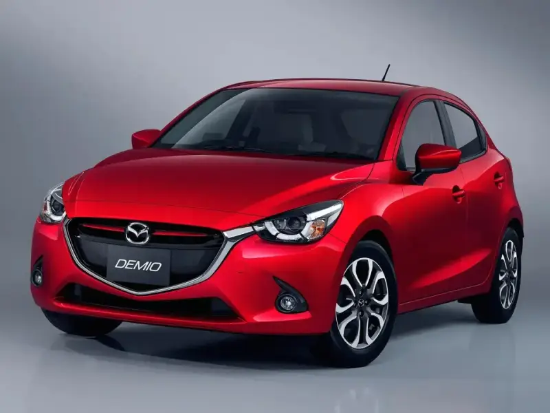 Czerwona Mazda Demio z błyszczącym grillem i reflektorami.